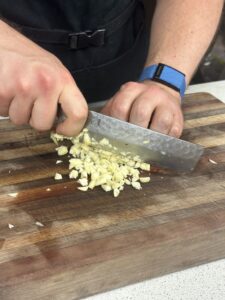 chef using knife skills to mince garlic