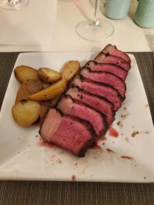 Rare picanha steak on a plate with roasted potatoes